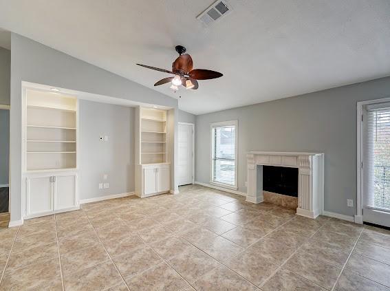 2425 Augusta Dr Unit 60, Houston, TX 77057 - unfurnished living room with vaulted ceiling, healthy amount of natural light, a ceiling fan, built in features, and a fireplace