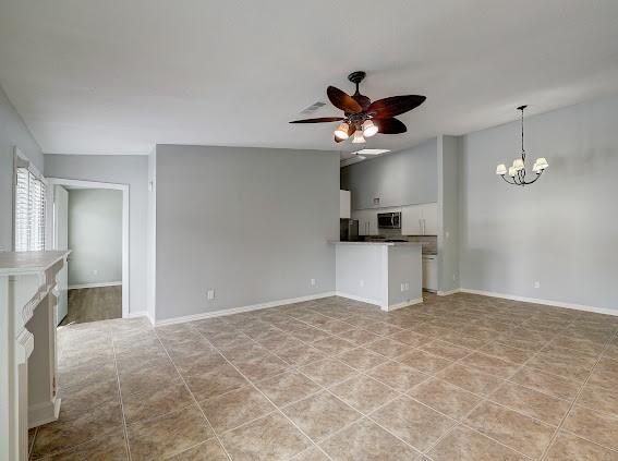 2425 Augusta Dr Unit 60, Houston, TX 77057 - unfurnished living room with a chandelier, ceiling fan, baseboards, and light tile patterned flooring