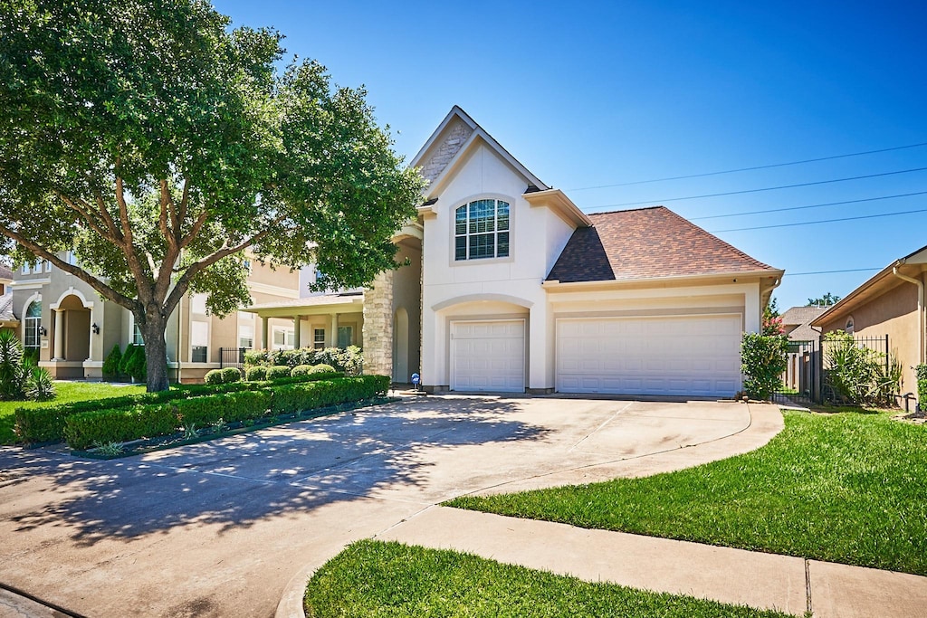 5227 Dawnington Pl, Sugar Land, TX 77479 - view of front facade featuring stucco siding, a front lawn, roof with shingles, concrete driveway, and a garage