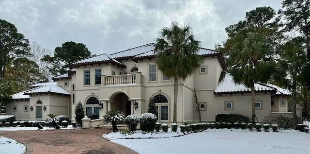 view of front of property featuring stucco siding, a tile roof, and a balcony