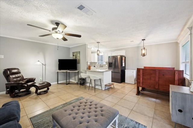 living area featuring light tile patterned flooring, ceiling fan, a textured ceiling, visible vents, and ornamental molding