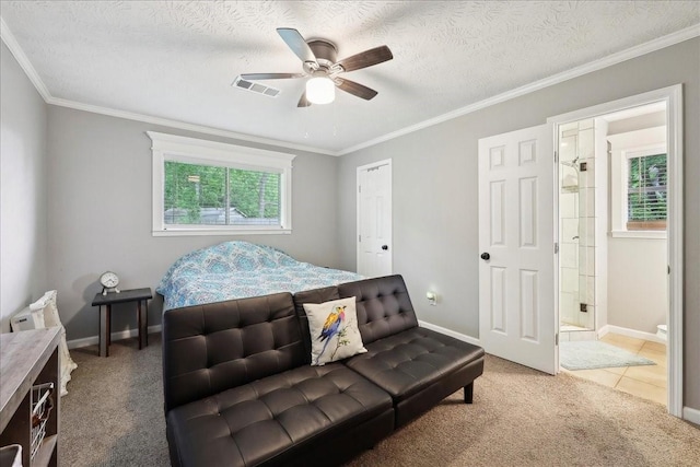 carpeted bedroom featuring baseboards, crown molding, ensuite bath, and visible vents