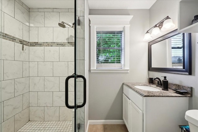 bathroom with vanity, baseboards, a shower stall, and tile patterned floors