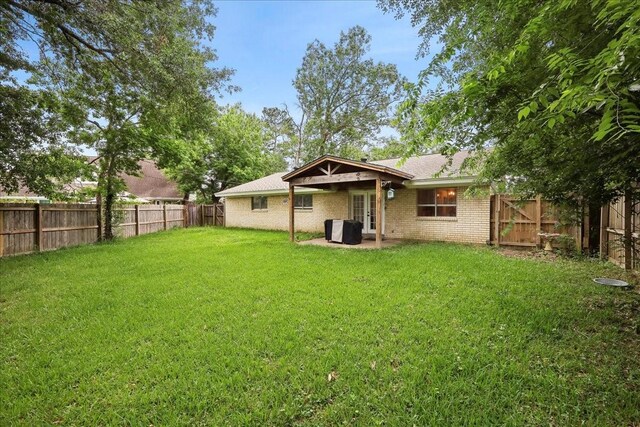 rear view of property featuring a patio, a fenced backyard, french doors, brick siding, and a lawn
