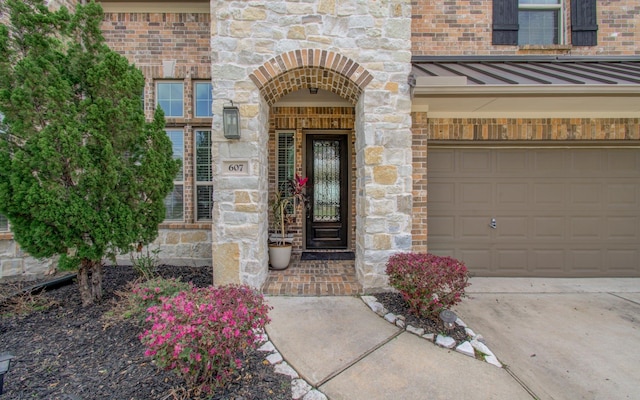 view of exterior entry featuring brick siding, concrete driveway, metal roof, stone siding, and a standing seam roof
