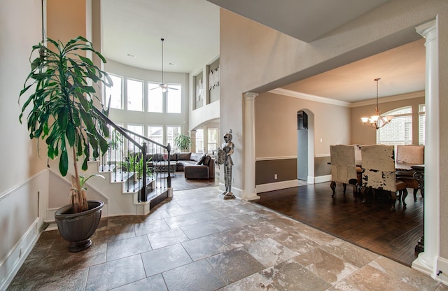 foyer entrance with arched walkways, a healthy amount of sunlight, crown molding, and baseboards