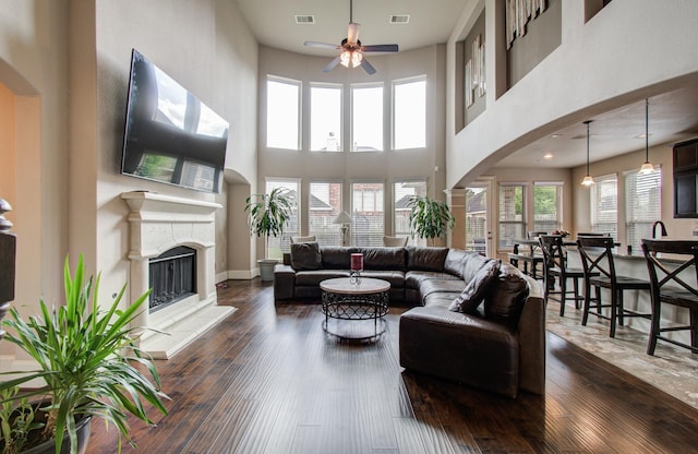 living area with dark wood-type flooring, visible vents, arched walkways, and ceiling fan