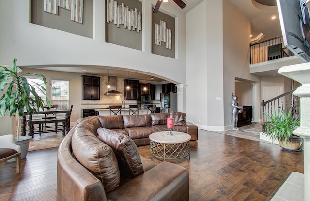 living room with baseboards, ceiling fan, stairs, wood finished floors, and arched walkways