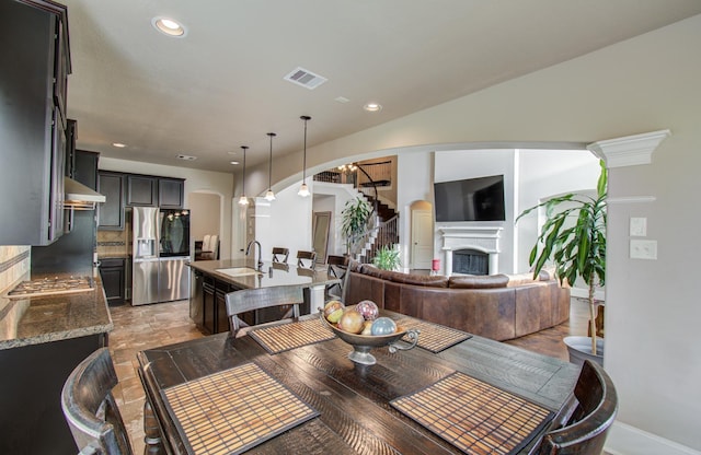 dining room with visible vents, stone finish flooring, recessed lighting, arched walkways, and a fireplace