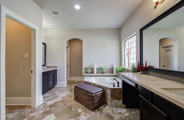 bathroom with baseboards, visible vents, two vanities, a sink, and a bath