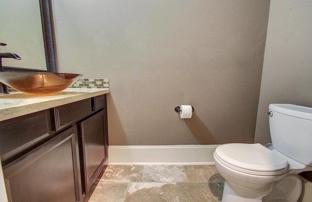 bathroom featuring decorative backsplash, baseboards, toilet, and vanity