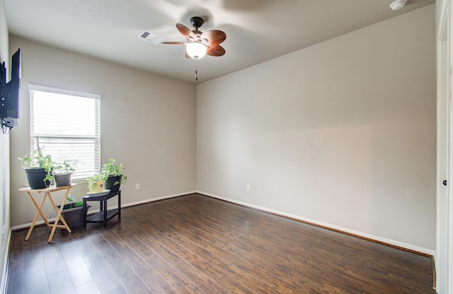 unfurnished room with dark wood-type flooring, a ceiling fan, visible vents, and baseboards