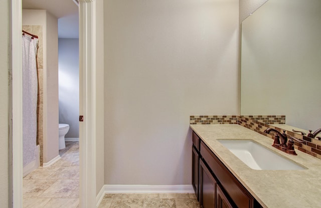 full bath featuring vanity, toilet, baseboards, and backsplash