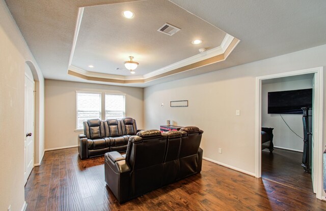 living room featuring a tray ceiling, visible vents, dark wood-style flooring, and crown molding