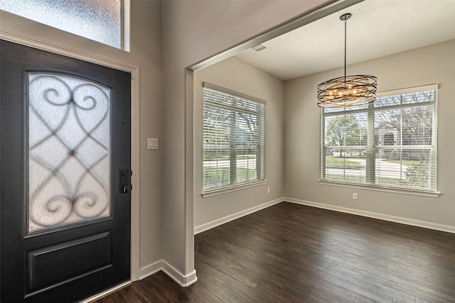 entryway with an inviting chandelier, baseboards, and dark wood-style flooring