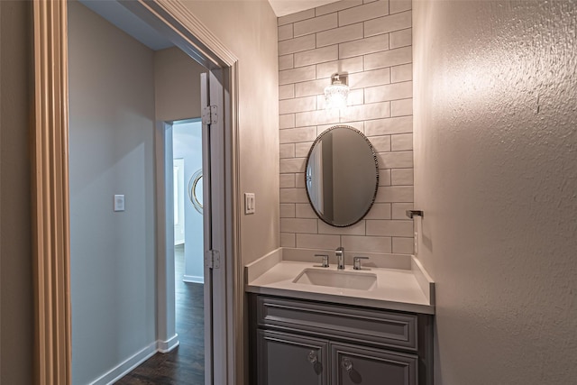 bathroom with baseboards, backsplash, wood finished floors, and vanity
