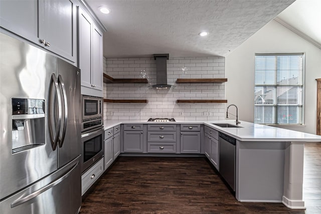 kitchen with a sink, wall chimney range hood, gray cabinets, appliances with stainless steel finishes, and open shelves