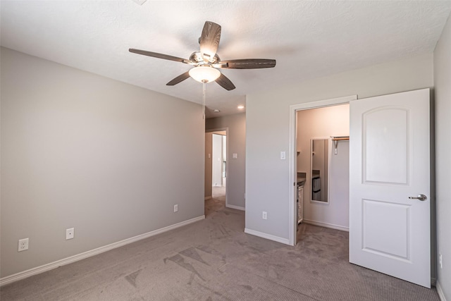 unfurnished bedroom featuring a walk in closet, a ceiling fan, a closet, carpet floors, and baseboards