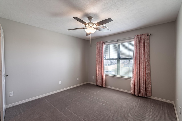 spare room with a textured ceiling, a ceiling fan, dark colored carpet, and baseboards
