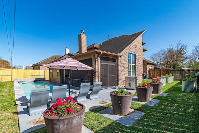 back of house with a fenced backyard, a yard, a fenced in pool, a chimney, and a patio area