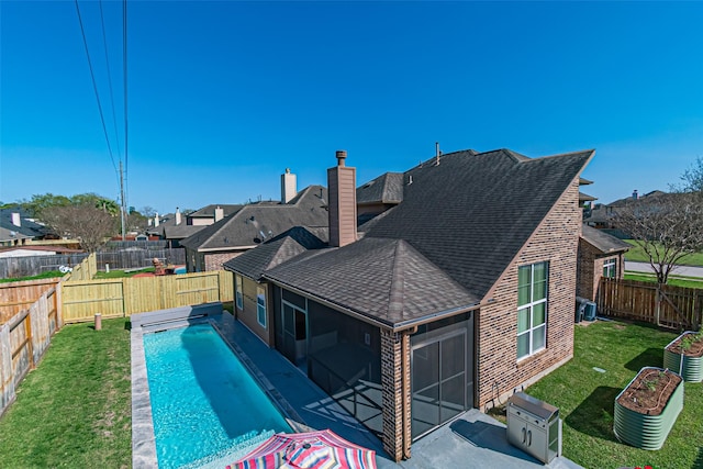 rear view of property with roof with shingles, a fenced backyard, a chimney, a garage, and a lawn