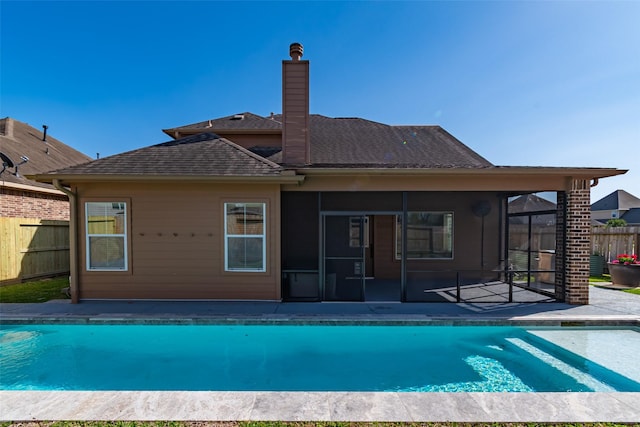 back of property with a fenced in pool, a sunroom, a chimney, and fence