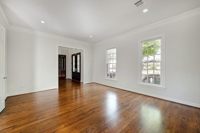 empty room with crown molding, visible vents, and wood finished floors