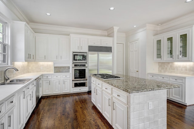 kitchen with decorative backsplash, built in appliances, a sink, and dark wood-style floors