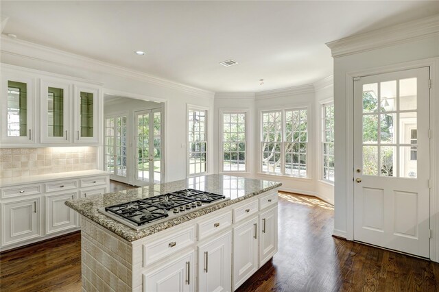 kitchen with visible vents, dark wood-style flooring, ornamental molding, stainless steel gas stovetop, and light stone countertops