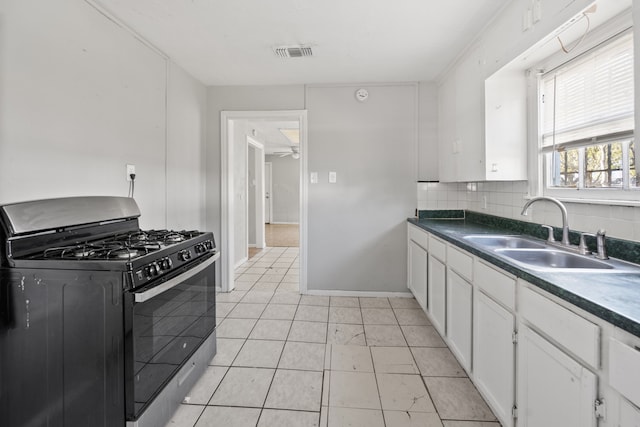 1017 Canadian St, Houston, TX 77009 - kitchen featuring visible vents, a sink, gas range oven, white cabinetry, and decorative backsplash