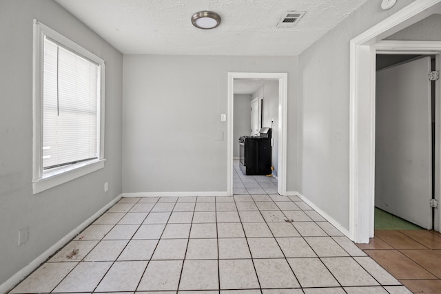 1017 Canadian St, Houston, TX 77009 - spare room with baseboards, visible vents, washer / dryer, light tile patterned flooring, and a textured ceiling