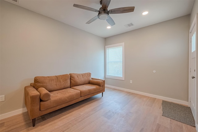 living room featuring baseboards, visible vents, light wood-type flooring, and a healthy amount of sunlight