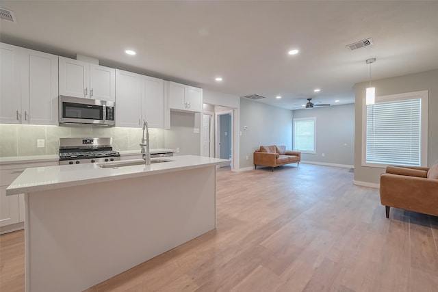 kitchen with a sink, visible vents, stainless steel appliances, light countertops, and light wood-style floors