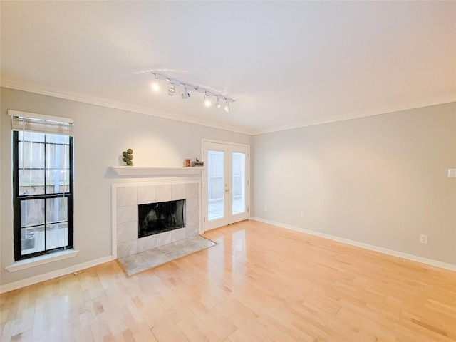 unfurnished living room with light wood-type flooring, crown molding, and french doors
