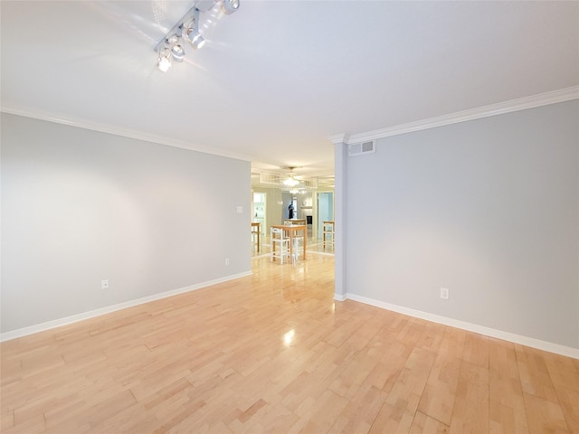 empty room with ornamental molding, baseboards, light wood finished floors, visible vents, and a ceiling fan
