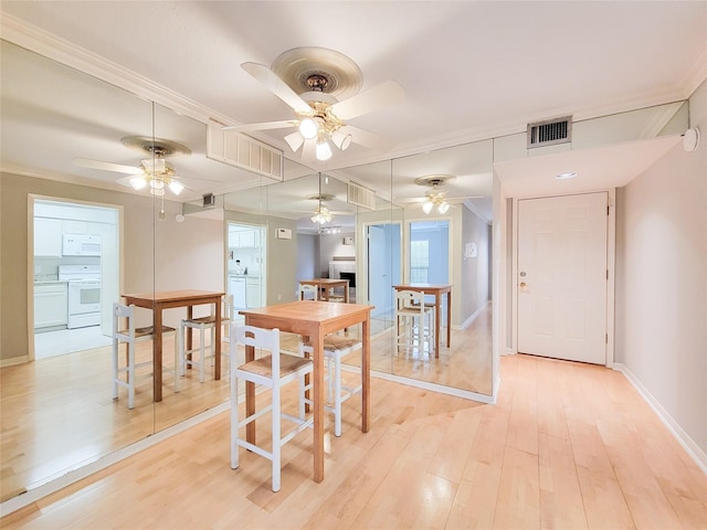 dining space featuring visible vents, light wood finished floors, baseboards, ornamental molding, and a ceiling fan