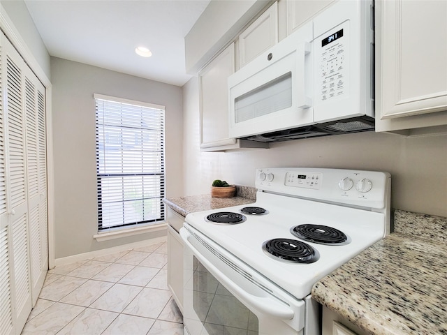 kitchen with white cabinetry, light stone counters, and white appliances
