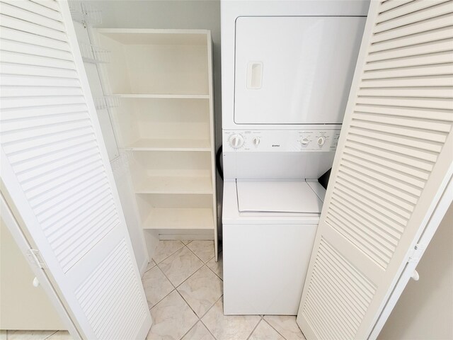 clothes washing area featuring stacked washer and dryer, marble finish floor, and laundry area