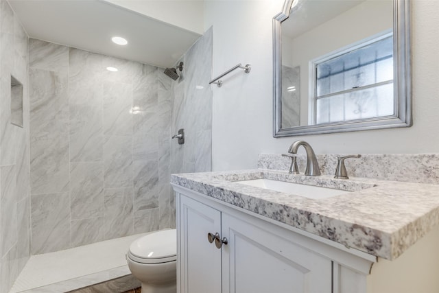 bathroom with vanity, toilet, and tiled shower