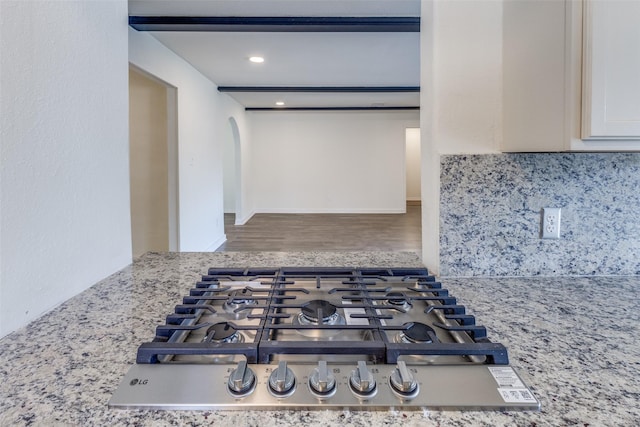 interior space featuring arched walkways, tasteful backsplash, wood finished floors, stainless steel gas stovetop, and recessed lighting