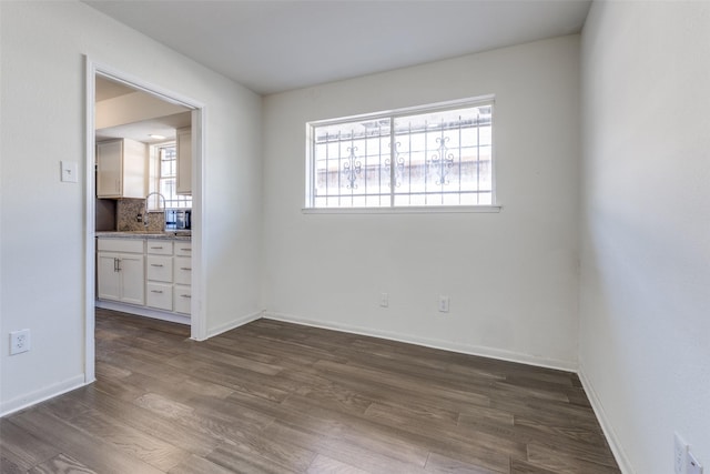 spare room with baseboards, dark wood-style floors, and a sink