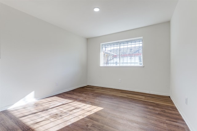 empty room with recessed lighting, baseboards, and wood finished floors