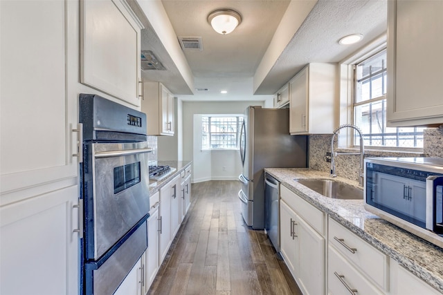 kitchen featuring appliances with stainless steel finishes, decorative backsplash, a sink, and visible vents
