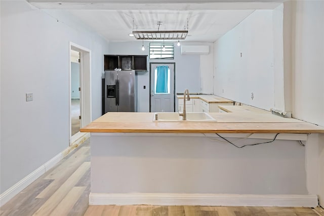 2025 Avenue N 1/2 Ave N 1/2, Galveston, TX 77550 - kitchen featuring a sink, stainless steel refrigerator with ice dispenser, an AC wall unit, light wood-style flooring, and a peninsula
