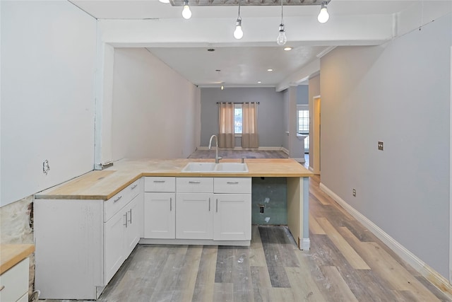 2025 Avenue N 1/2 Ave N 1/2, Galveston, TX 77550 - kitchen with a sink, butcher block countertops, light wood finished floors, a peninsula, and white cabinets