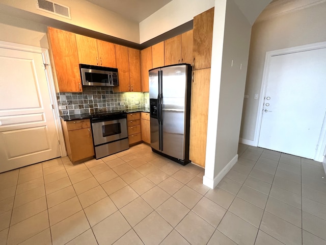 3333 Allen Pkwy Unit 1804, Houston, TX 77019 - kitchen with stainless steel appliances, dark countertops, light tile patterned flooring, decorative backsplash, and brown cabinetry