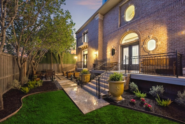 exterior space featuring brick siding, a patio area, french doors, and fence