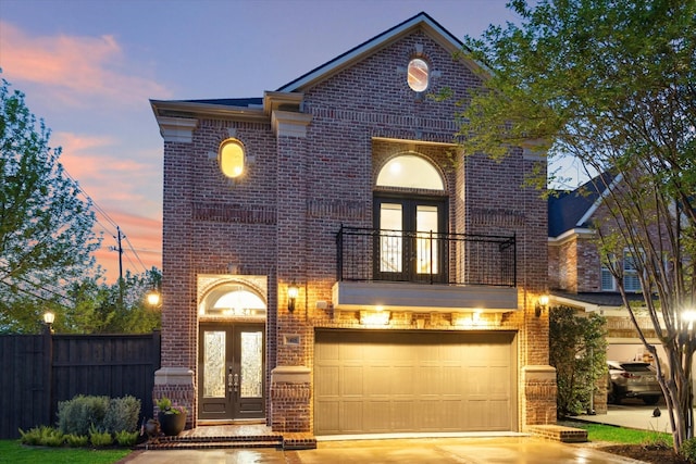 view of front of property with french doors, driveway, brick siding, a garage, and a balcony