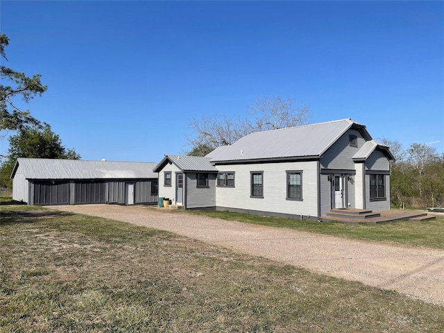 134 E N St, Goliad, TX 77963 - view of front of house featuring a metal roof, an outdoor structure, a front lawn, and an outbuilding