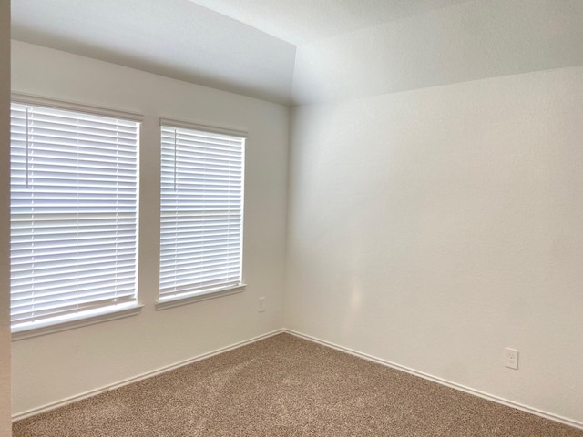 empty room featuring baseboards, carpet floors, and vaulted ceiling